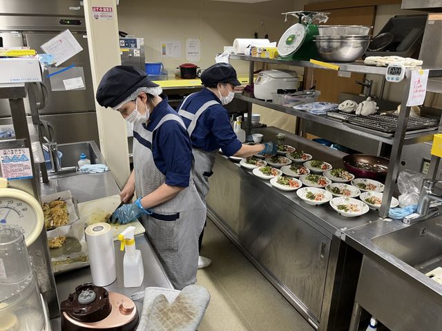 スタッフが料理を手作業でキッチン キッチン 栄養満点の食事を提供するキッチンスタッフを募集中！安全で美味しい料理の提供が私たちの使命です。