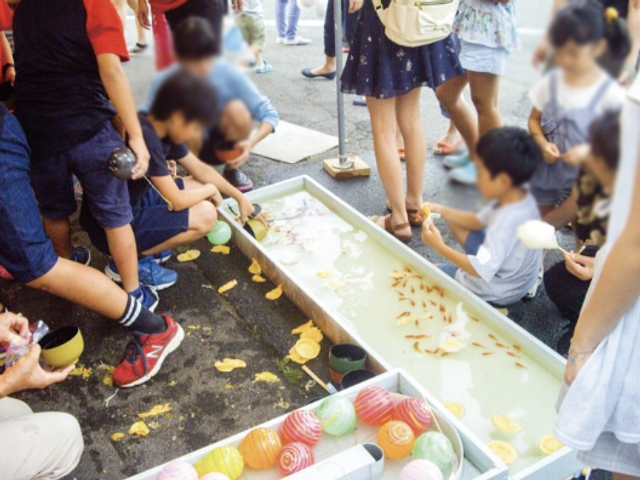 お祭りの様子 多目的室 お祭りの雰囲気の中で、参加者たちが金魚すくいやヨーヨー釣りを楽しんでいます。楽しい交流が生まれる場です。