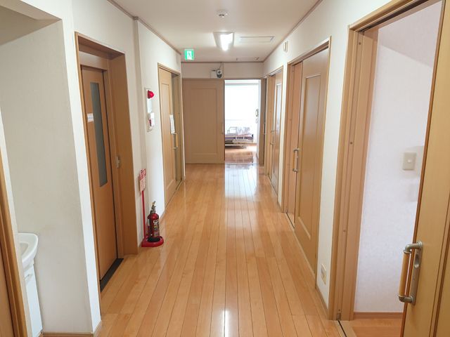 明るい廊下のイメージ 廊下 床が木目調の温かみのある廊下は、清潔感があり明るく、ゆったりとした空間です。各部屋への出入りもしやすく配慮され、心地よい職場環境が広がっています。