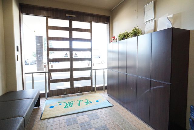 明るいエントランス風景 玄関 ゆったりとした受付エリアです。清潔感のある室内と誘導しやすい明るい出入り口が特徴です。