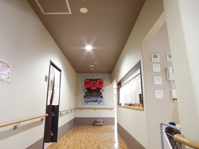 明るい廊下の一角 廊下 手すり沿いの温かみのある空間に、掲示物が配置され安全かつ快適です。
