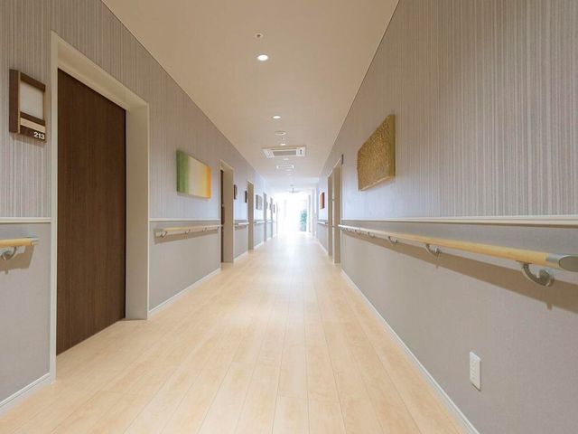 廊下の明るいイメージ 通路 広々とした廊下は、明るく清潔感があり、壁にはアートが飾られています。手すりが整備されており、安全に配慮された設計となっています。