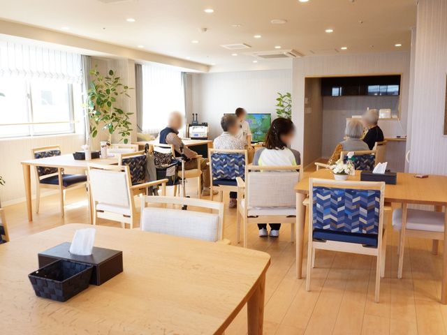 快適な明るい食堂 多目的スペース 木の温もりが感じられる食堂で、入居者様がリラックスしながら会話を楽しんでいます。ゆったりとした時間が流れるこの場所で、あなたも支援を始めませんか。