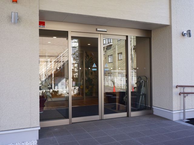 明るいエントランスの外観 玄関 広々としたエントランスは、訪れる方を暖かく迎え入れます。明るく開放的な空間で、ご利用者様の快適な生活が始まります。