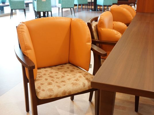 テーブルと椅子が複数置かれている共有スペースである。椅子は２種類ある。床は木目調の素材を採用している。