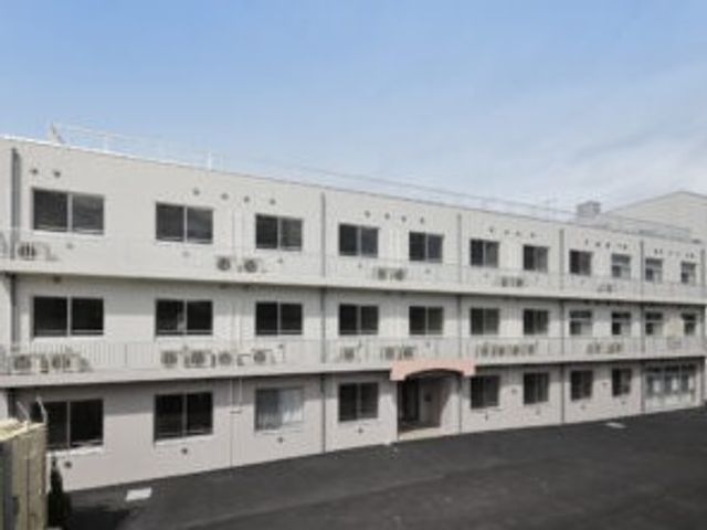 施設の外観 外観   白い3階建ての建物で、整った窓並びが印象的です。出入口前までアスファルトが広がり、落ち着いた雰囲気です。