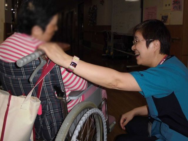 温かい交流の廊下 廊下 明るい廊下で、スタッフが利用者と笑顔で親しげにお話ししています。温かい雰囲気です。