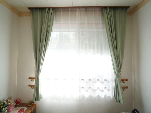 居室の明るい窓辺 居室 ゆったりとした窓辺で、外の光が柔らかく室内を照らしています。採光とプライバシーが考慮されたカーテンが心地よい時間を約束します。