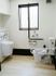 白を基調とした内装に、壁の下側と手すり、窓枠に黒を取り入れたトイレである。便座の正面に深さのある洗面台を設置している。