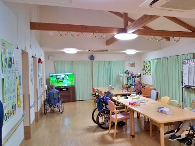 共有スペースの様子 多目的室 ゆとりある多目的室では、テレビを見る方々やテーブルで過ごす方がいらっしゃいます。木の温もりを感じる空間で日々のひとときをお過ごしいただけます。