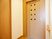 サムネイル 茶色の落ち着いた色合いのエレベーター。小さな窓が複数ついたデザイン性のある扉になっている。横の壁にはシンプルな行先ボタンが設置されている。