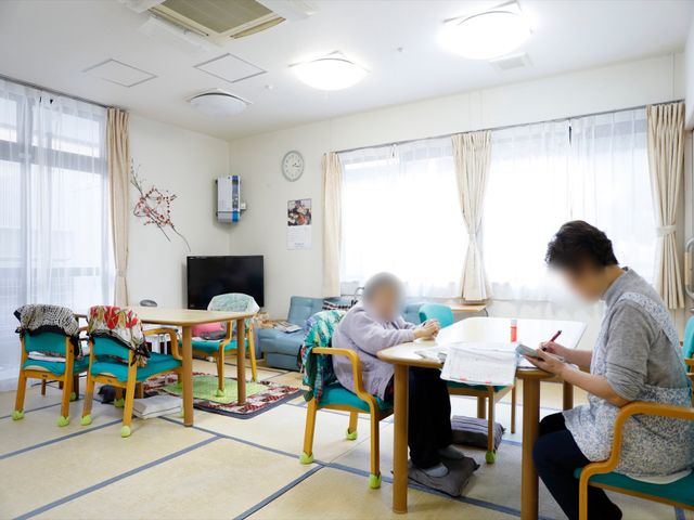 明るい居室の一角 共有スペース ゆったりとした居室で、利用者がのんびりとした時間を過ごしています。自然光が差し込む和やかな雰囲気は、日々の業務にも穏やかさをもたらします。