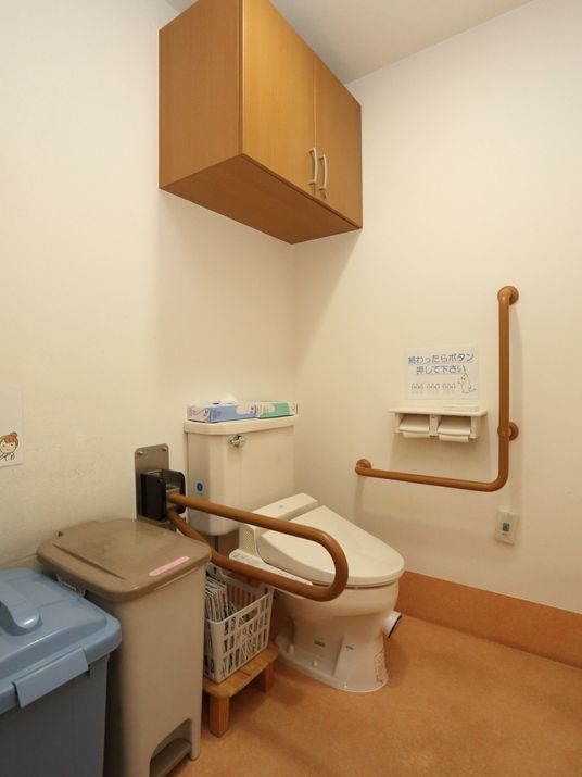 便器の両側に手すりが設置されているトイレ。一方は壁にL字型で、もう一方は可動式になっている。便器の周りには十分なスペースがある。
