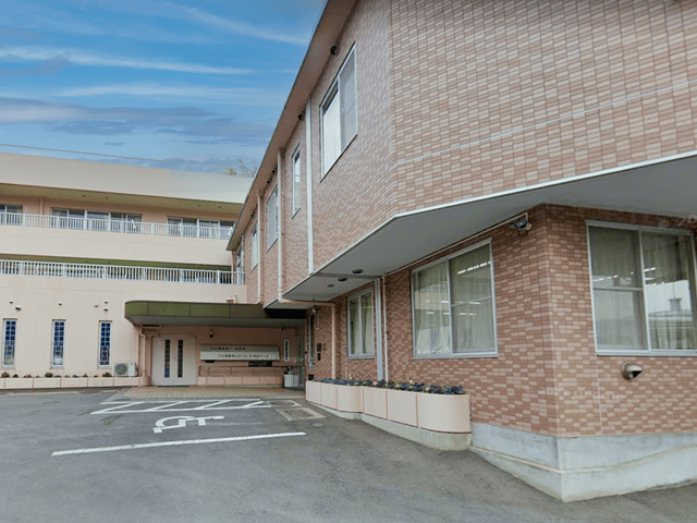 建物外観の出入口 外観   落ち着いた色合いの建物外観で、出入口前まで車で近づきやすいスペースがあります。働く場としても導線を確認しやすい印象です。