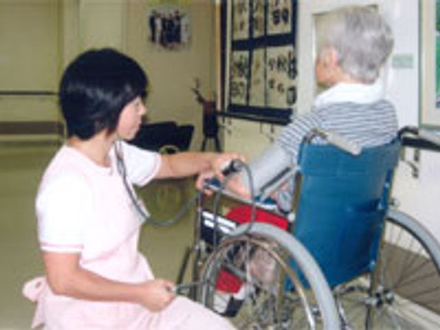 会話する看護師と利用者の廊下 廊下 車椅子の利用者と親しげに会話する様子です。共に過ごす安心感を醸し出しています。