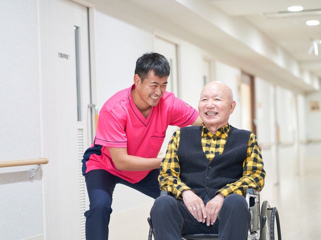 笑顔のスタッフと利用者の廊下 廊下 スタッフが笑顔で利用者のサポートをしています。明るく清潔な廊下は温かい雰囲気です。
