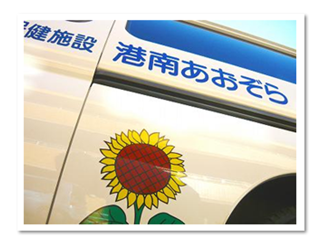 ひまわりのステッカー車両 看板 ひまわりが描かれた鮮やかなステッカーが印象的な移動車です。目を引くデザインになっています。