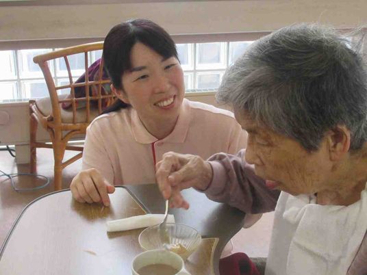 微笑む介護士と利用者の食事風景