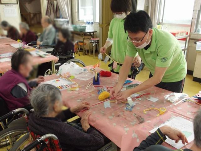 アクティビティ中の様子 多目的室 自然光が差し込む明るい部屋で、利用者とスタッフが一緒に作業を楽しんでいます。