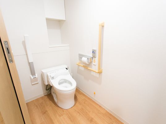 施設の写真 トイレは清掃が行き届いていて清潔感がある。便座の両側に手すりがある。壁にナースコールが設置されている。