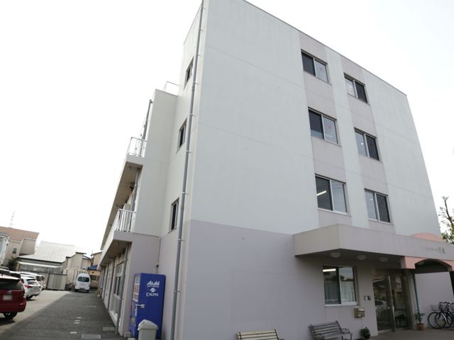 清潔感ある建物外観 外観 清潔で明るい印象を与える建物です。ベンチが置かれた静かな通りに面しており、ゆったりとした時間が流れている様子が伺えます。