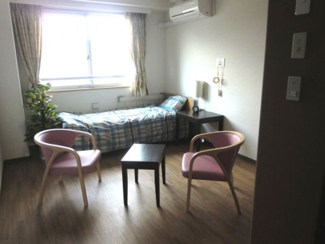 居室内の清潔な配置 居室 広々とした居室は、落ち着いた色合いで統一され、快適な個人空間を提供しています。窓からは自然光が差し込み、明るい雰囲気を演出しています。