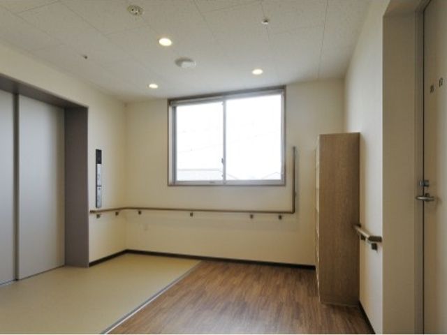 清潔感のある居室空間 エレベーターホール 窓から自然光が入り明るい居室です。壁には手すりが設置され、安全に過ごせる工夫がされています。