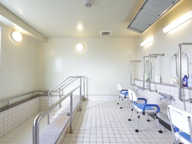 手すり付き洗面台 浴室 安全に配慮した手すりと座面のある洗面台が並ぶ清潔な浴室です。スタッフのサポートも充実しており、安心してご利用いただけます。