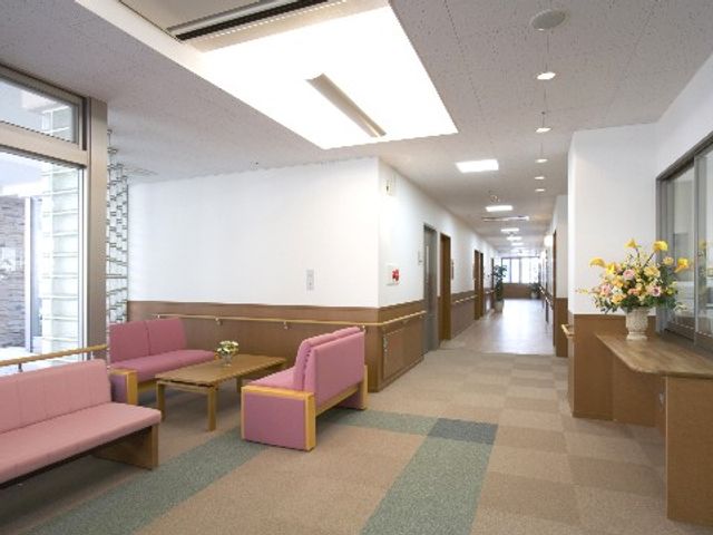 清潔感のある明るい廊下 館内 綺麗で明るい通路は広々としており、快適な空間づくりに配慮されています。待合スペースには落ち着いた色のソファが配置されております。