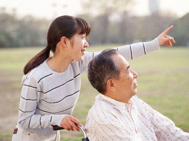 笑顔の女性と車椅子の男性 介護 笑顔で会話を楽しむ二人の姿は、日々の充実した暮らしを物語っています。外の新鮮な空気も心地よさを加えてくれることでしょう。