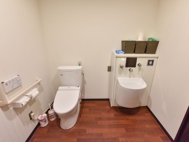 清潔なトイレ空間 トイレ 安全な手すり付きのトイレと洗面台が設置され、清潔感のある空間が保たれています。使いやすさと利便性が考慮された環境です。