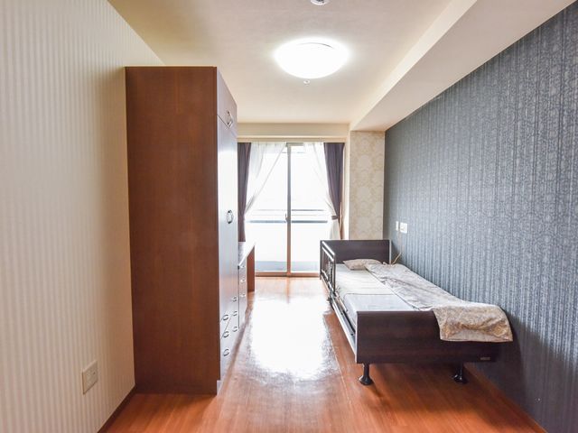 落ち着いた色の居室 居室 ゆったりとした居室は日当たりが良く、プライバシーを大切にする方に適しています。木目調の家具が温もりを感じさせ、くつろぎの時間をお過ごしいただけます。