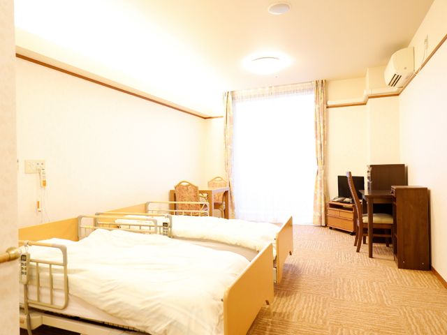 暖かみのある居室空間 居室 柔らかな色合いの壁と家具が、ゆったりとした雰囲気を演出しています。安全にも配慮されたベッドが備えられており、快適な生活空間です。