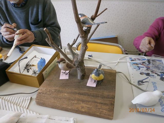 手作り作品の机 休憩室 手作りの小鳥の模型を制作する様子。リラックスした雰囲気の中で創作活動が行われています。