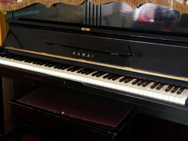 黒いアップライトピアノ ピアノ 共有スペースに配置されたピアノは、音楽好きな方々の憩いの場を提供しており、心地よいひとときを演出します。