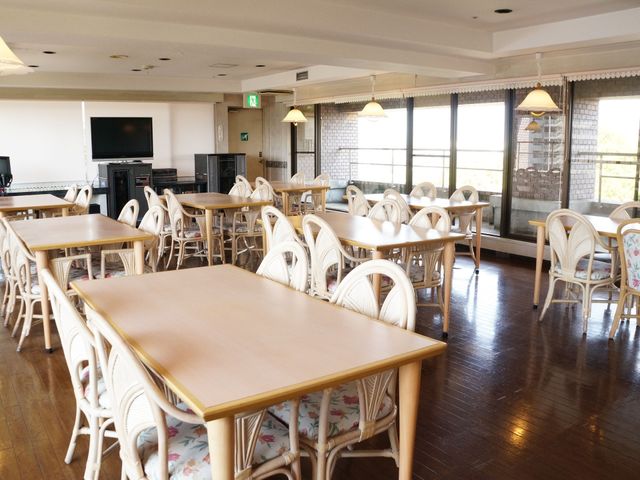 快適なダイニングルーム 展望レストラン  ゆとりある木のテーブルが並ぶ明るい食堂です。日差しを取り込む大きな窓からは、穏やかな光が差し込みます。