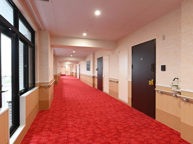 赤いカーペットの廊下 廊下 清潔感のある明るい廊下を備えた環境です。手すり付きで安全な移動が可能です。