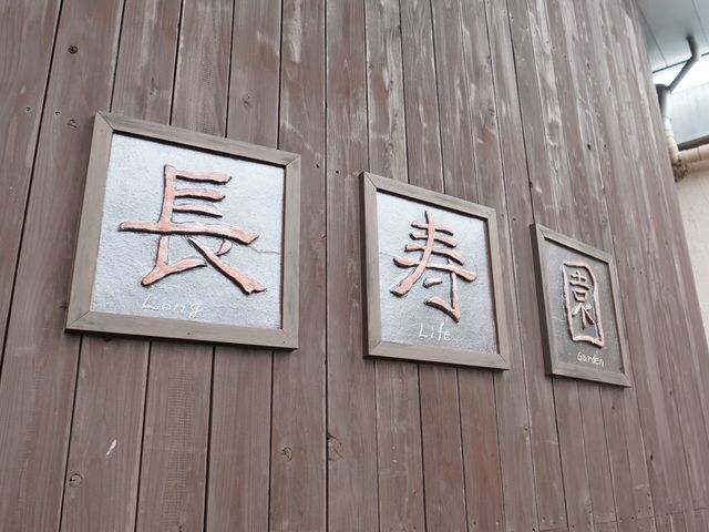 看板のクローズアップ ロゴ 木の壁に埋め込まれた、心を落ち着かせる漢字の表札が目を引きます。