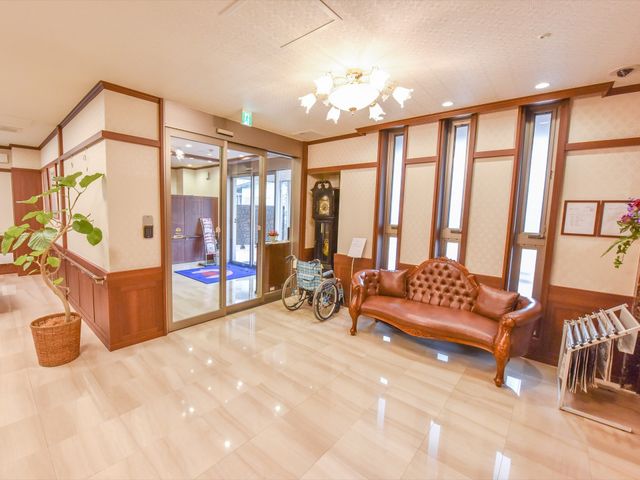 廊下にベンチと車椅子 エントランス 落ち着いた雰囲気の廊下には、ゆったりとくつろげるソファが配置されており、訪れる人々に安らぎを提供しています。