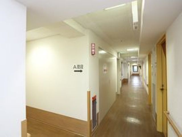広々とした明るい廊下 廊下 ゆとりある設計の廊下は、快適な移動ができるようになっております。周りにはプライバシーが守られた居室の入口が並んでいます。