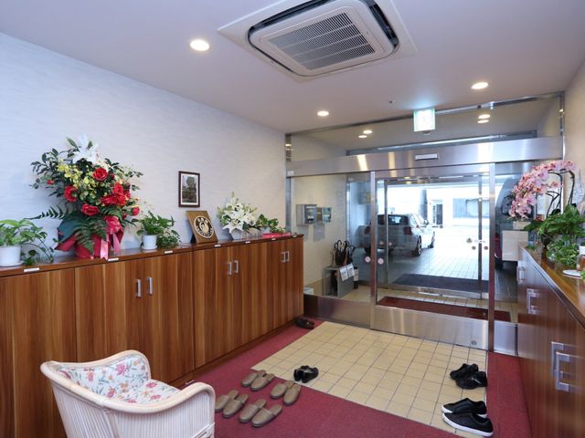 エントランスの花と椅子 玄関 心地よい印象を与えるエントランスには、多彩な植物が飾られており、訪れる人々を暖かく迎えています。