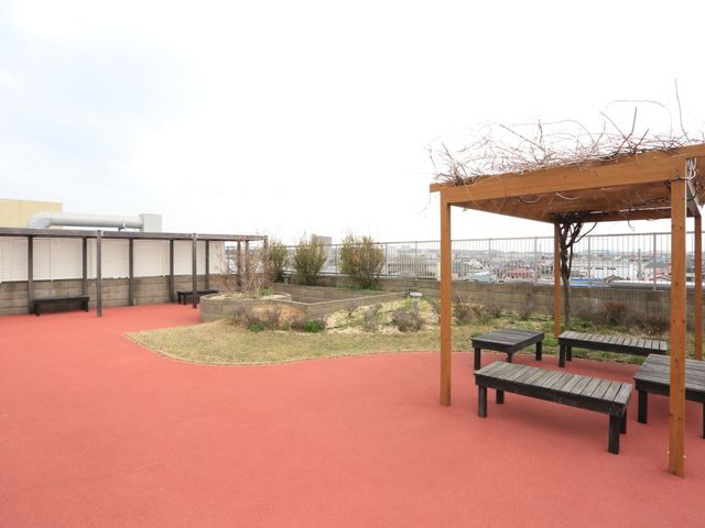 屋上の休憩スペース 屋上庭園 開放的な中庭では、木のベンチで新鮮な空気をお楽しみいただけます。静かで落ち着いた雰囲気が、リラックスタイムの贅沢を演出します。