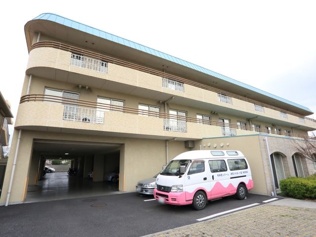 広々とした建物の外観 外観 柔らかな色合いの建物の外観を見ることができ、敷地内には専用車両も停めてあります。ここでの仕事は、十分な環境が整っていることが伺えます。