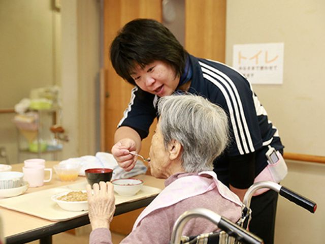 食事介助中の居室 居室 広々とした居室で、丁寧な食事介助が行われています。日常のサポートを重視した環境です。
