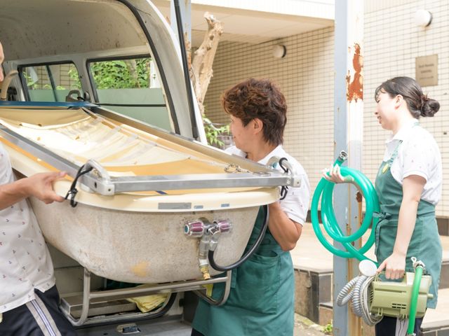 介護用ベッド搬出シーン 機能訓練室 スタッフが手際よく介護用ベッドを搬出しています。皆さん、仕事に慣れた印象を与え、安心して任せられる雰囲気です。