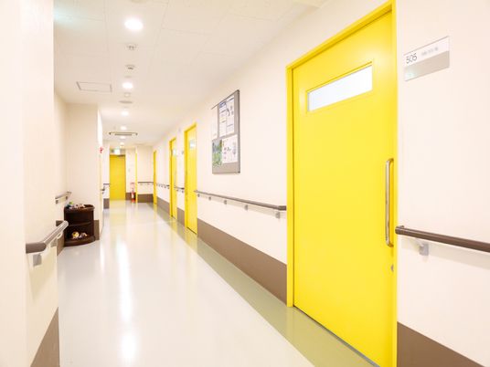 鮮やかなイエローの引き戸が、ポップなデザインの廊下である。壁の両側には、茶色の手すりが付いていて安全面にも配慮してある。