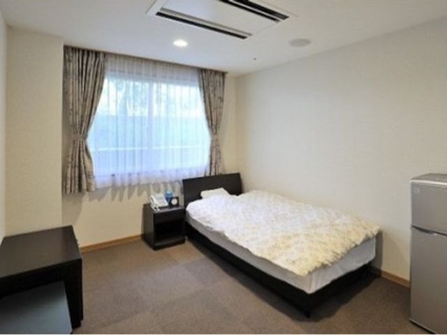 清潔な居室 家族宿泊室 落ち着いた色合いの居室には、大きなベッドと必要最低限の家具がそろっています。