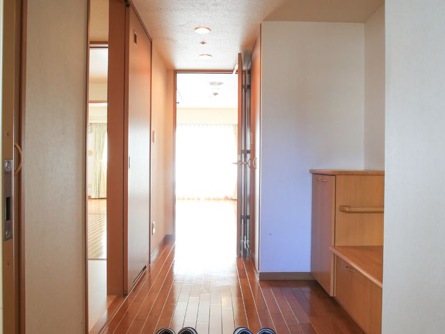 廊下の明るい居室入口 居室 温かみのある色合いの居室入口には、スリッパが丁寧に揃えられており、安らぎと秩序を感じさせる空間が広がっています。