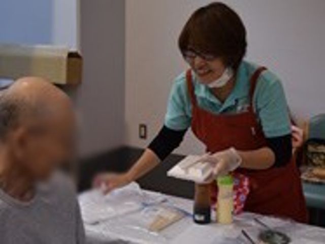 笑顔の会話がある居室 居室 スタッフが親しみやすい笑顔で利用者と会話しています。共に過ごす時間が和やかに流れています。