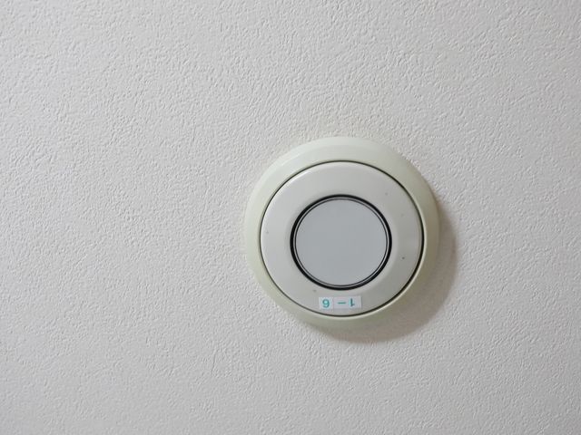 白壁に取り付けられたセンサー 非常用ブザー 職員も利用者様も快適に過ごせる温度管理が行き届いた環境です。快適な気温で、日々の業務に専念いただけます。
